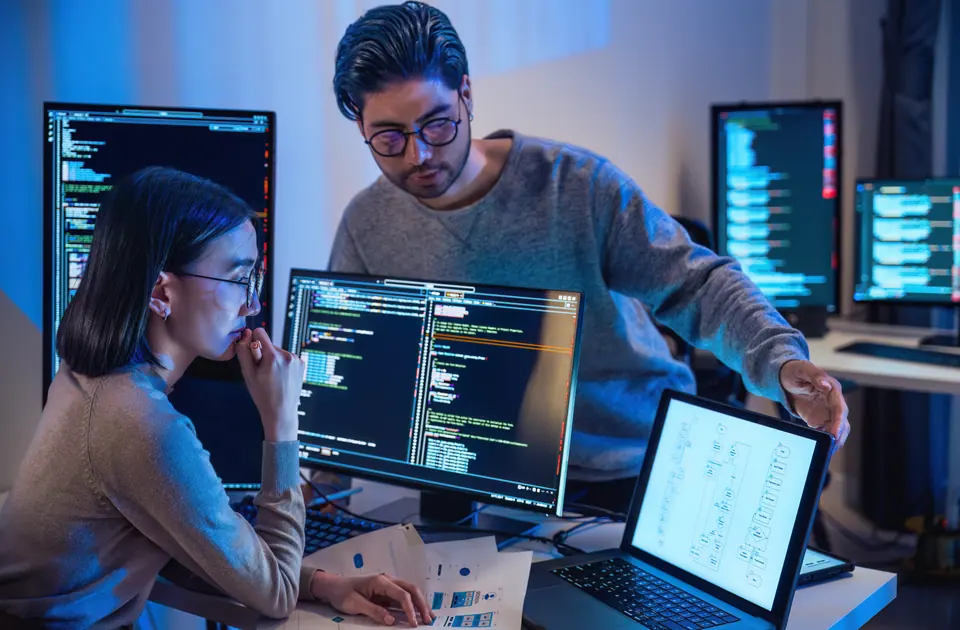 Asian and Indian Developer DevOps team discussion about coding promgram with software computer at night in office