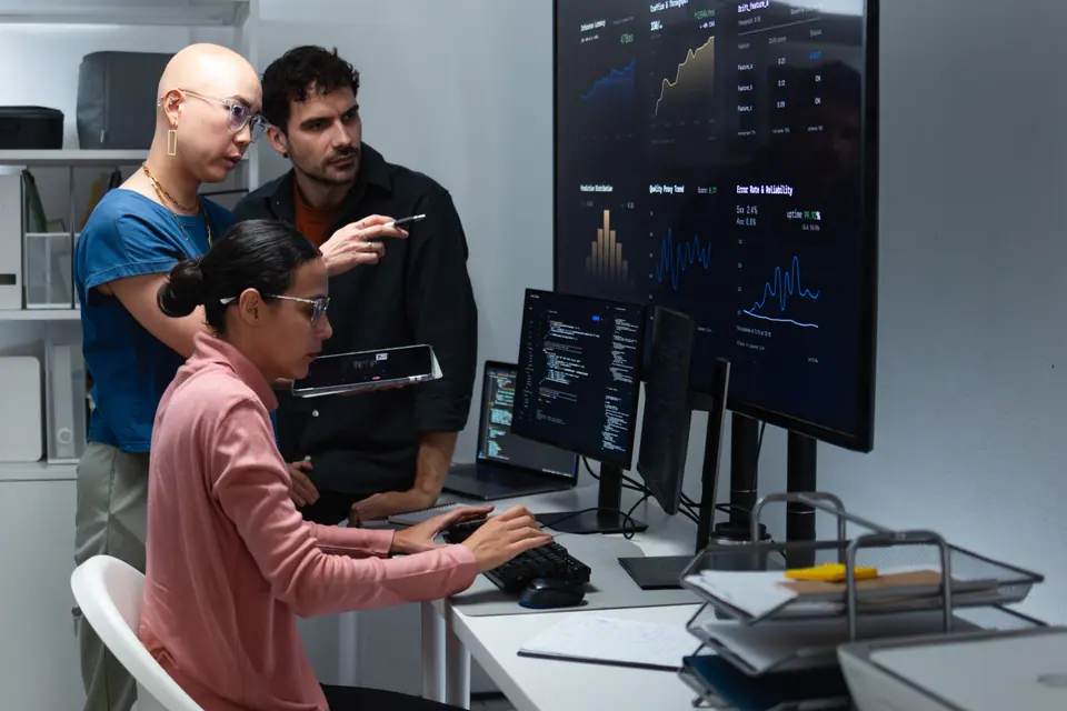 DevOps team checking monitoring data and application trends, reviewing operational metrics, analyzing observability metrics on large screen in control…