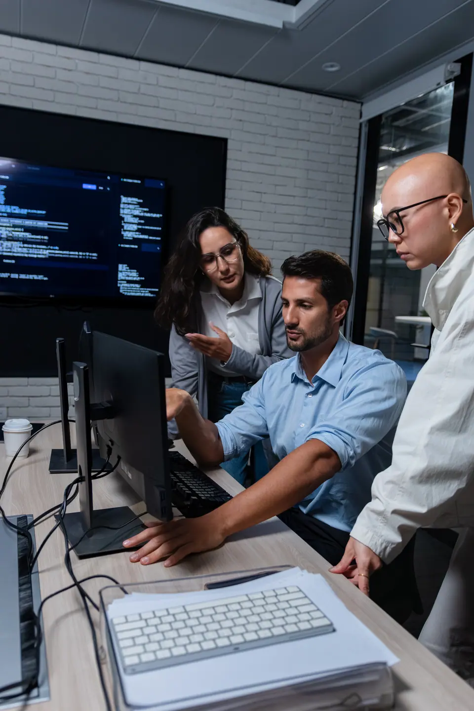 Programmer team collaborating around monitor for technical analysis, coding review, and AI software project discussion