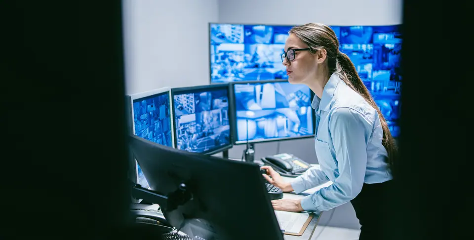 Security female operator reviewing data in control room with technology