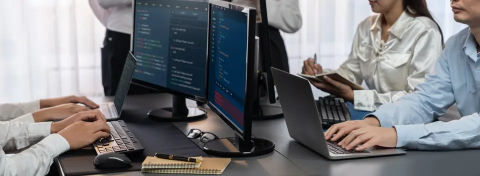 Software development team working together in office, coding script display on computer monitor