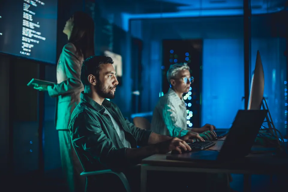 Technology team monitoring computer systems and working together in modern data center office