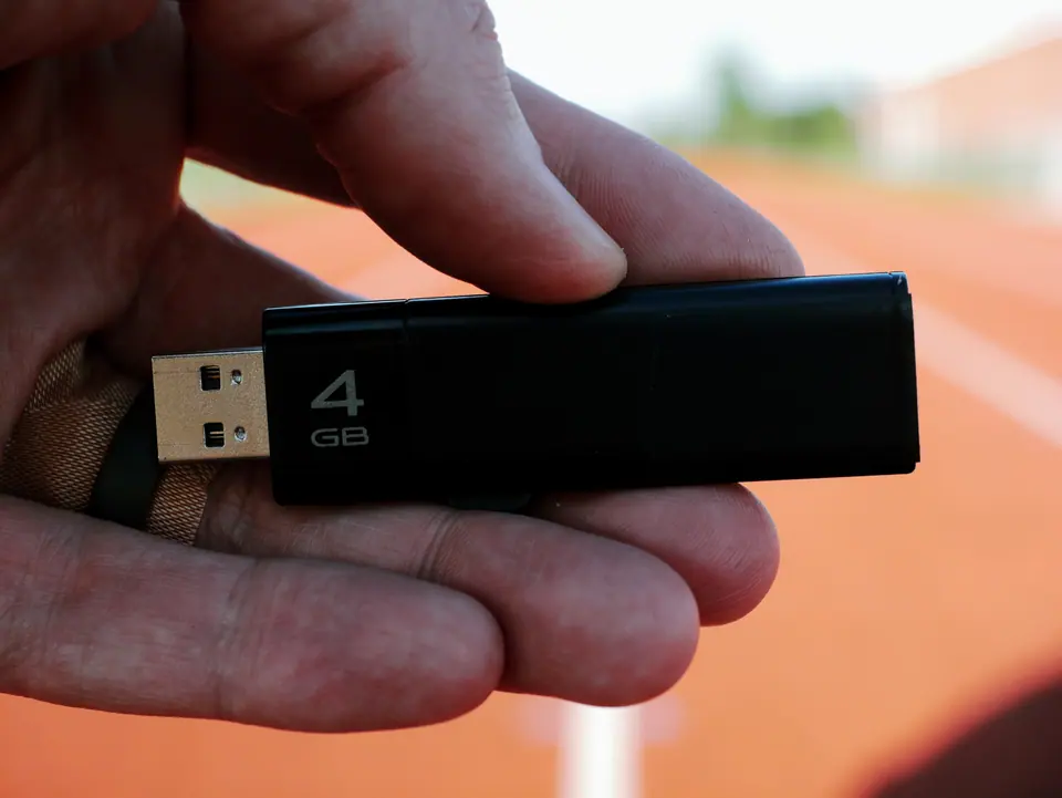 Unsuspecting man finds lost USB thumb drive on ground illustrating malicious USB drop attack - Cybersecurity Information Technology Concept