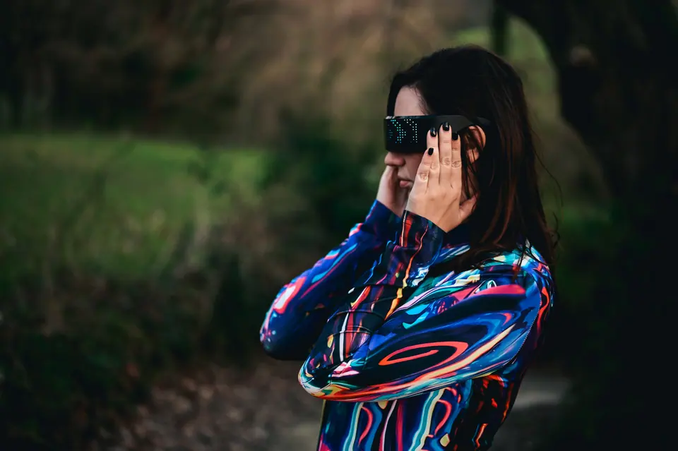 Young woman wearing LED glasses, interacting with digital world outdoors